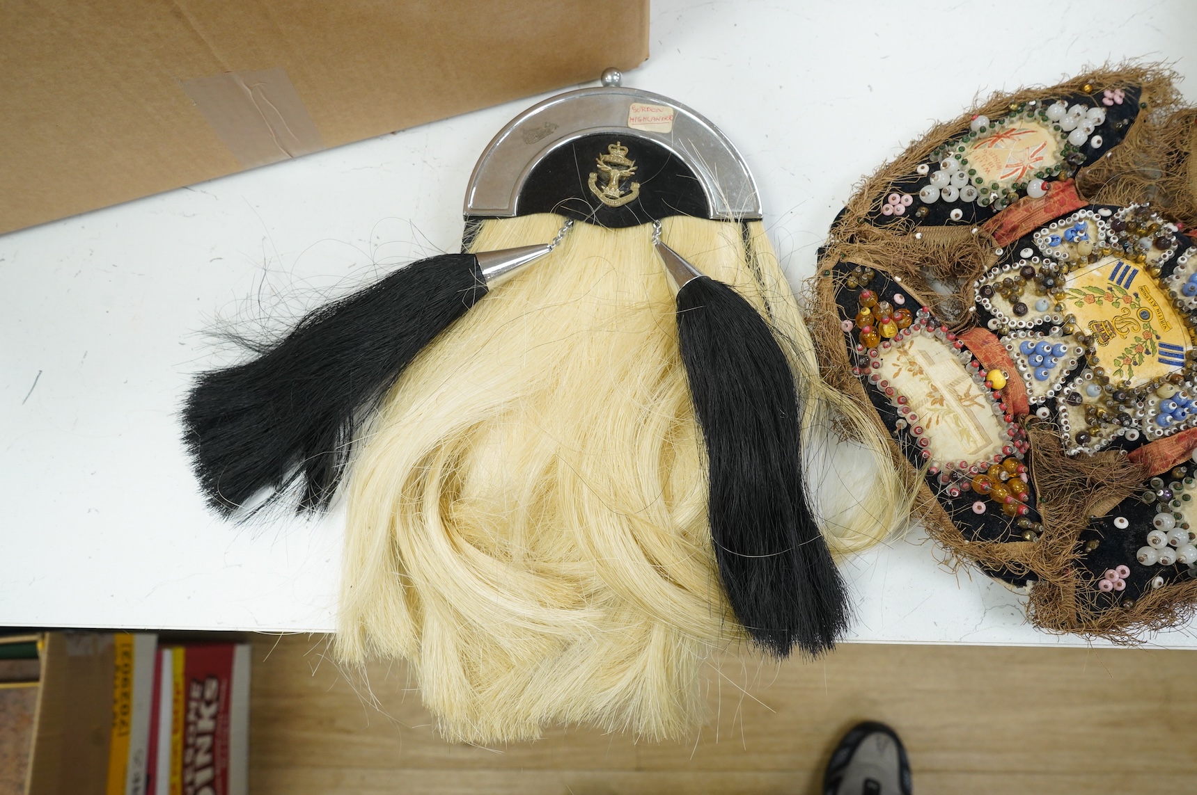 A collection of militaria, etc. including; a Gordon Highlander’s kilt and sporran, three early 20th century Union Flags, a Victorian beaded ‘sweetheart’s’ cushion, two empty First World War Princess Mary Christmas tins,